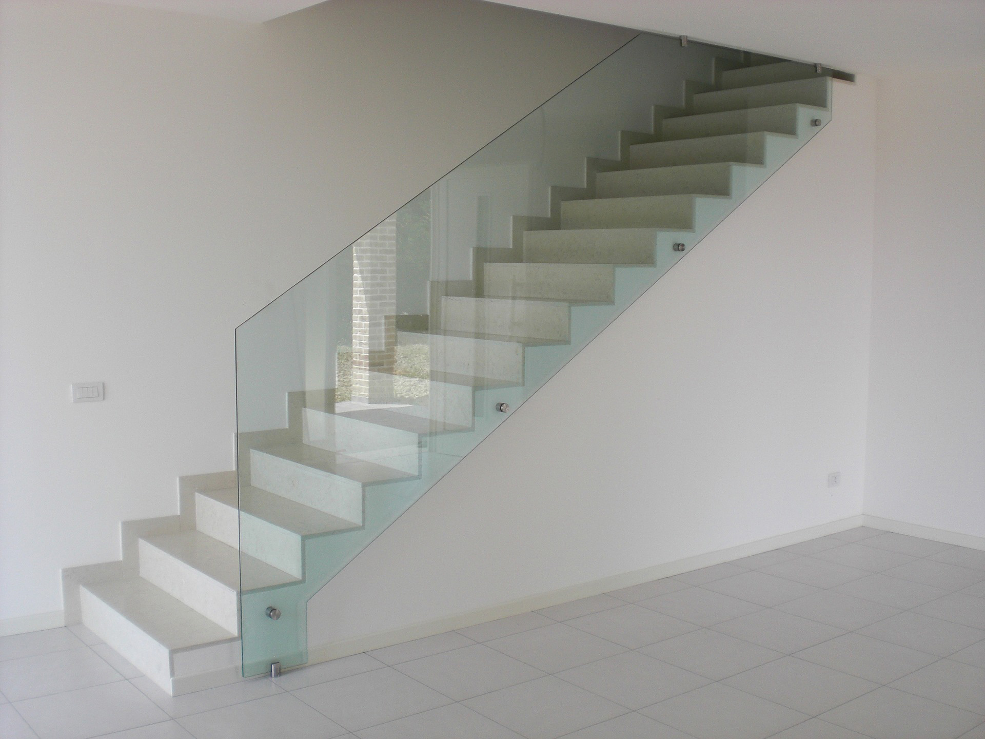A sheet of tempered glass acting as a staircase railing. The glass has a noticeable green tint.
